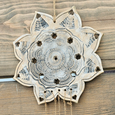 Keramikdekor in Form einer Blume mit geometrischen Mustern und kleinen Löchern.