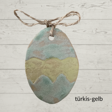 Türkise und gelbe Keramikosterei mit gewelltem Muster und Schnur.