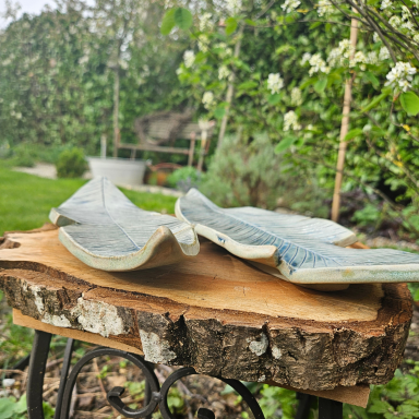 Zwei keramische Schalen auf einem Holzscheit, im Hintergrund Gartenpflanzen.