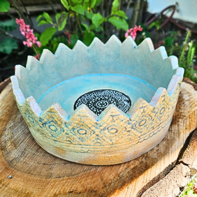 Dekorative, hellblaue Keramikschale mit gewelltem Rand und ornamentalem Muster.