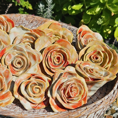 Ein Korb mit handgefertigten Rosen aus Keramik in warmen Farben.