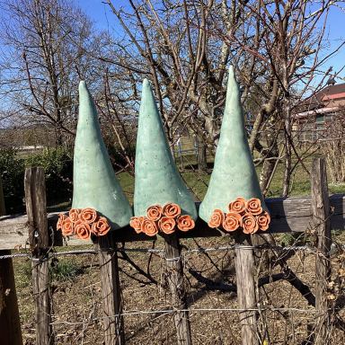 Drei Gartenstecker Keramik stecken als Zaunhocker auf einem Staketenzaun