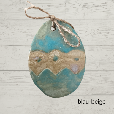 Bunt gefärbtes, blau-beiges Osterei mit einer Schnur zum Aufhängen.