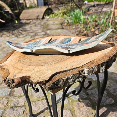 Deko Schale auf einem holzarten Tisch im Garten, umgeben von Pflanzen und Natur.