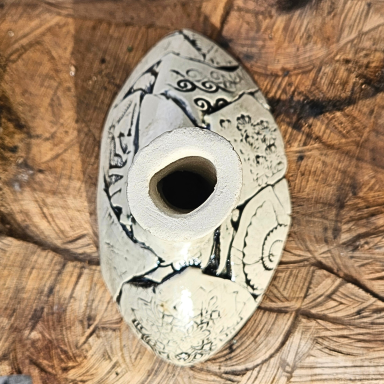 Ein ovaler Keramikbehälter mit kunstvollen schwarzen Mustern auf hellem Grund.