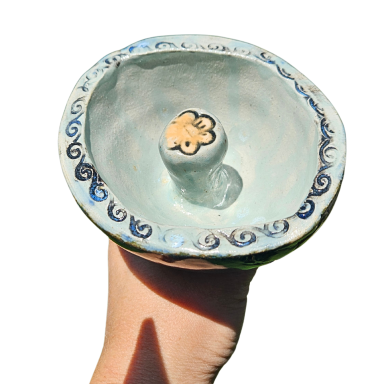 Eine handgehaltene Keramikschale mit blauen Mustern und einer zentralen Erhebung.