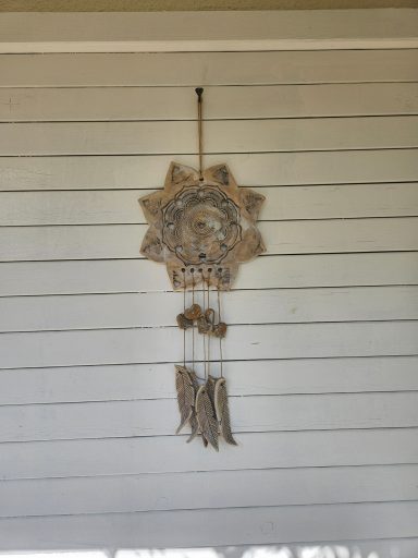 Traumfänger aus Naturmaterialien mit Schnüren und Ornamenten an einer Wand.