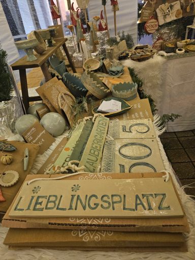 Dekorative Artikel und Beschilderungen auf einem Marktstand, darunter "LIEBLINGSPLATZ".