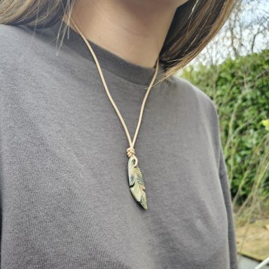 Eine Person trägt ein Halsband mit einem Anhänger aus Keramik.