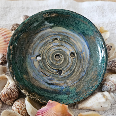 Eine glasierte, runde Schale mit spiralförmigem Design und mehreren Löchern.